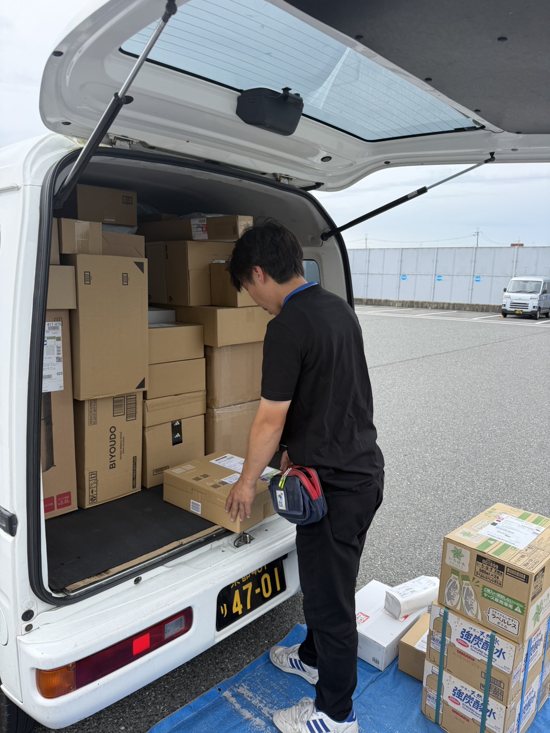 ドライバーが荷物を車に積む